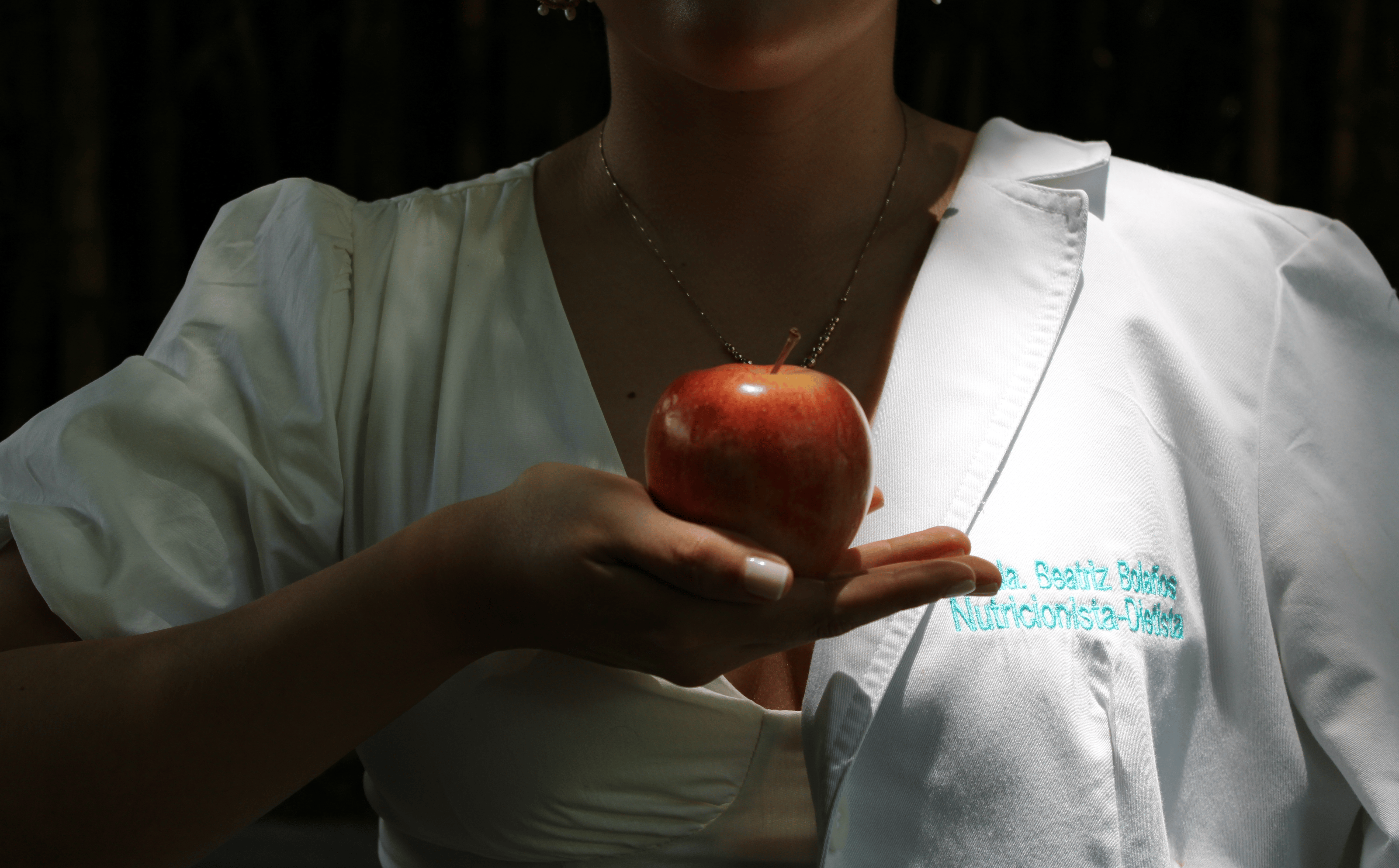 Mujer sosteniendo una manzana a la altura del pecho.